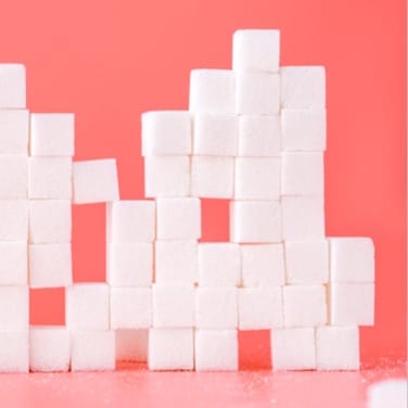 Sugar cubes stacked against a pink background