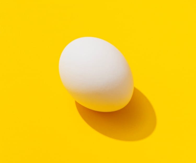 Egg balancing on a yellow background